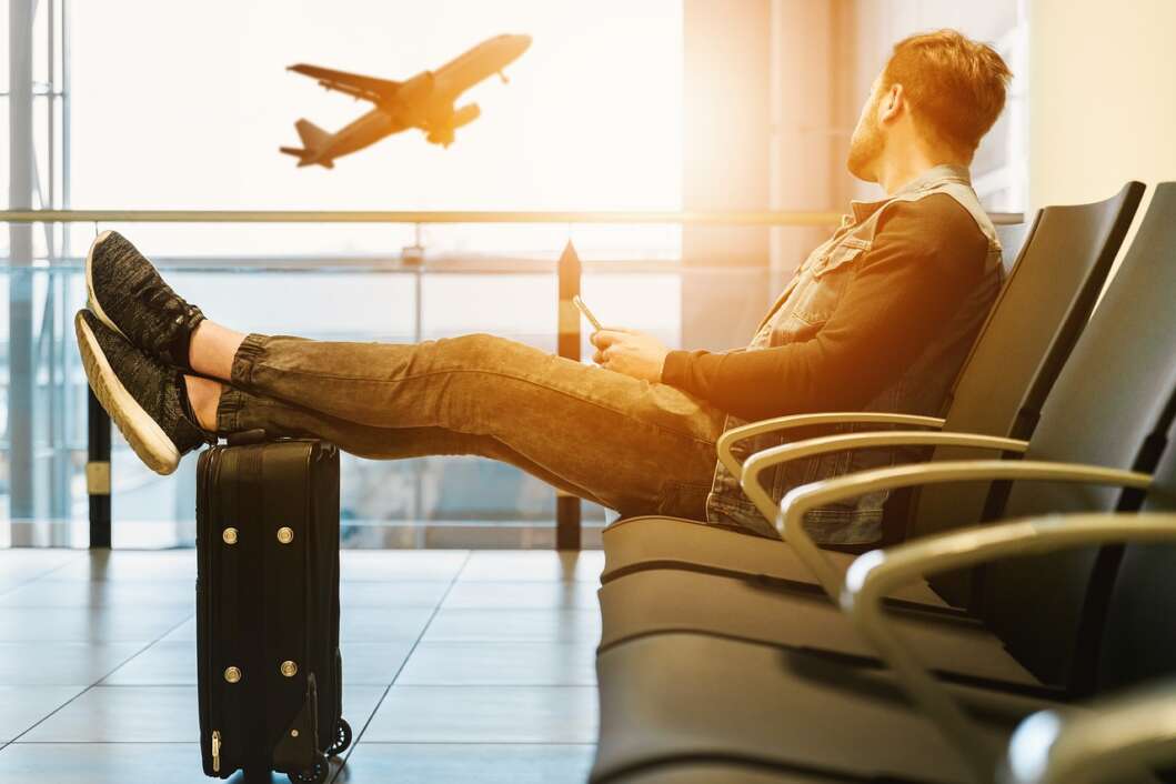 Putnik na aerodromu odmara i surfa po mobitelu čekajući let aviona
