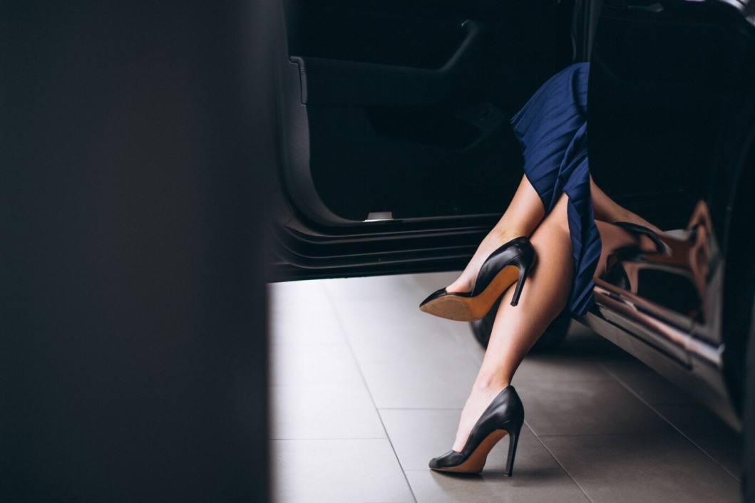 Žena sjedi u autu i pokazuje noge